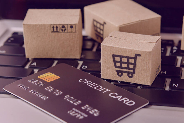 Online vásárlás. Hitelkártya és kartondoboz bevásárlókosár logóval a laptop billentyűzetén. Bevásárlási szolgáltatás az interneten. házhozszállítás - Fotó, kép