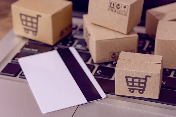  Shopping online. Credit card and cardboard box with a shopping cart logo on laptop keyboard. Shopping service on The online web. offers home deliver - Fotoğraf, Görsel