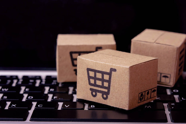 Shopping online. Cardboard box with a shopping cart logo on laptop keyboard. Shopping service on The online web. offers home deliver - Фото, зображення