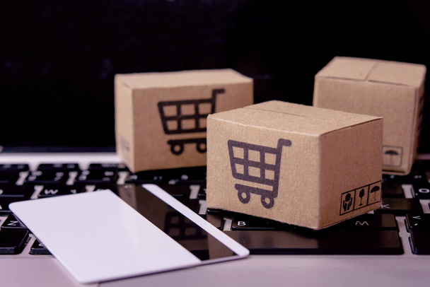  Shopping online. Credit card and cardboard box with a shopping cart logo on laptop keyboard. Shopping service on The online web. offers home deliver - Φωτογραφία, εικόνα