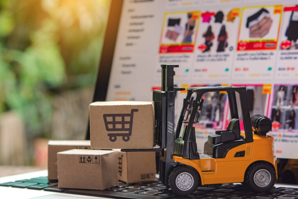 Forklift φορτωτής παλέτα με χάρτινα κουτιά ή δέμα σε laptop, Logistics και υπηρεσία παράδοσης για online αγορές - Φωτογραφία, εικόνα