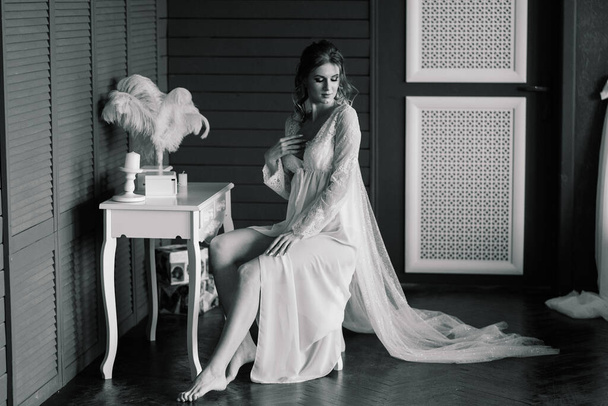 Gyönyörű menyasszony fehér csipke fehérnemű, csupasz váll ül egy hotelszobában, boudoir. Boldog esküvőt!. - Fotó, kép