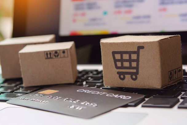 Online einkaufen. Kreditkarten- und Kartonschachtel mit einem Warenkorb-Logo auf der Laptop-Tastatur. Shopping-Service im Internet. bietet Hauszustellung - Foto, Bild