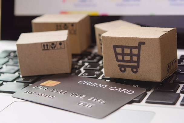 Ostoksia verkossa. Luottokortti ja pahvilaatikko, jossa on ostoskorin logo kannettavan tietokoneen näppäimistöllä. Ostospalvelu verkossa. tarjoaa kotiinkuljetus - Valokuva, kuva