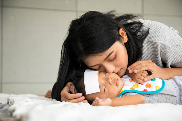 Asijské mladé matka pečovat samec dítě dostal horečku onemocnění v ložnici s kopií prostoru - Fotografie, Obrázek