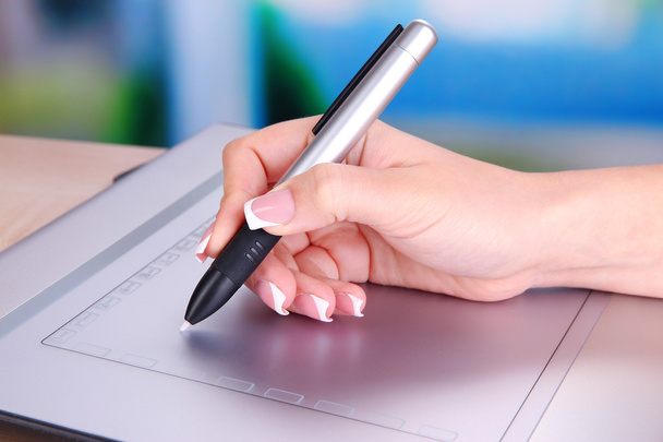 Female hand using graphics tablet on table on bright background - Photo, Image