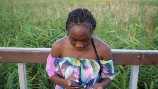 feliz señora afroamericana con saltos de teléfono cerca de pasamanos - Metraje, vídeo