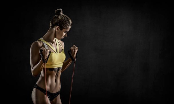 portrait young fitness woman performs exercise on blaack background with empty space for text, gym concept - Foto, afbeelding