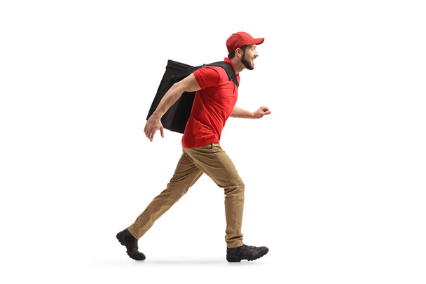 Full length profile shot of a food delivery guy running with a bag on his back isolated on white background - Фото, зображення
