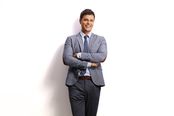 Professional young man leaning on a white wall and smiling at the camera - Foto, Imagen
