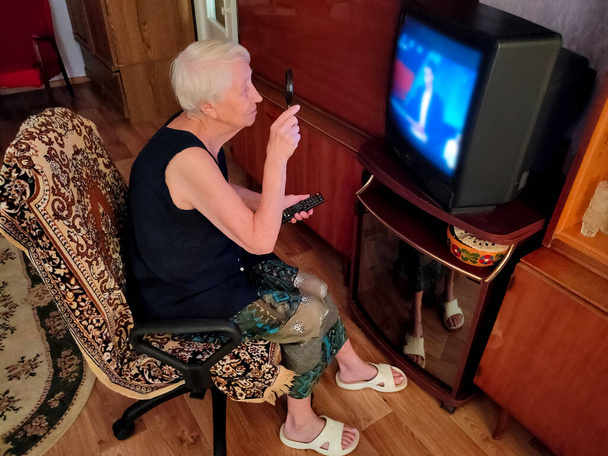 La donna anziana che vede male guardare la tv a casa. - Foto, immagini