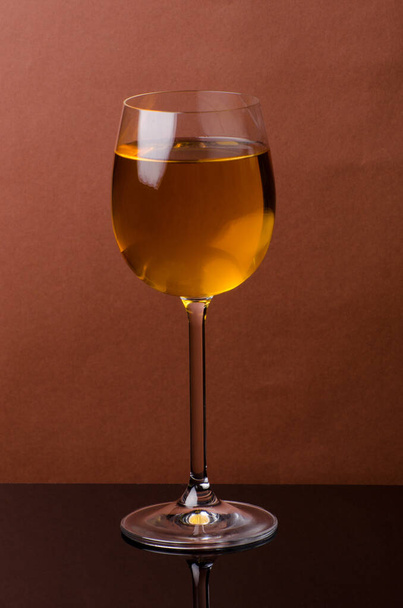 Una copa de vino blanco sobre un fondo marrón. Bodegón - Foto, imagen