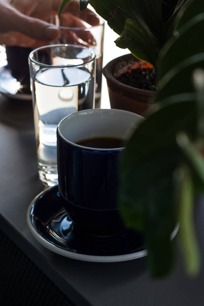 Mavi fincanlarda siyah ve koyu sabah kahvesi ve saksılarda yeşil bitkiler.. - Fotoğraf, Görsel