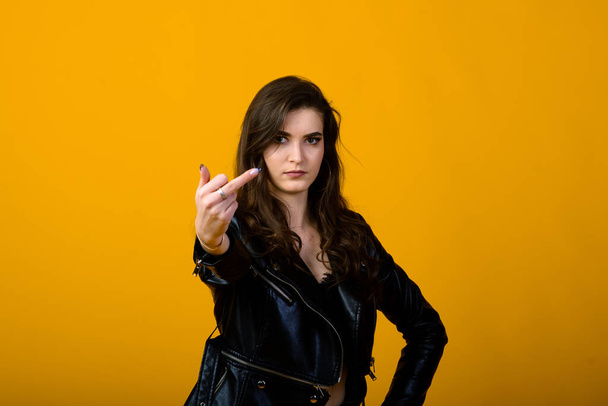 Portrait of a happy young brunette girl showing gestures and smiling, surprising isolated over yellow background. Emotional pic - Foto, afbeelding