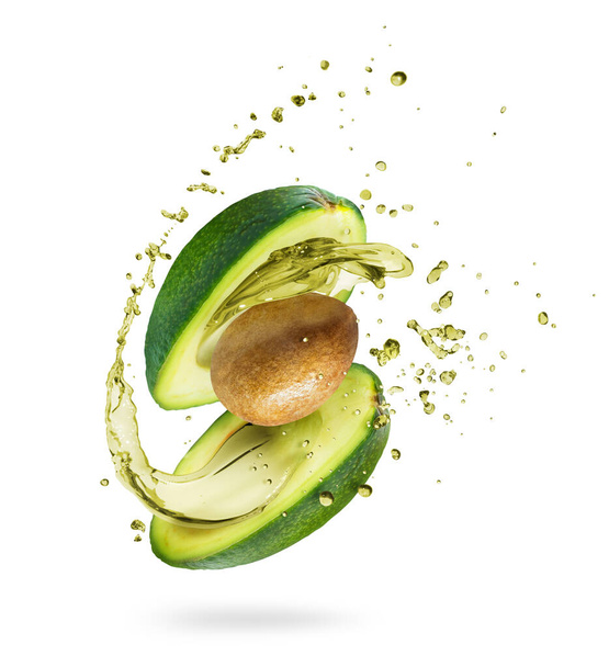 Sliced avocado with splashes of juice close-up, isolated on a green background - Foto, Imagem