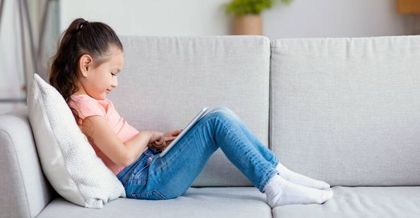 Ιαπωνικό κορίτσι παιδί χρησιμοποιώντας ψηφιακή ταμπλέτα κάθεται στο σπίτι, Πανόραμα - Φωτογραφία, εικόνα