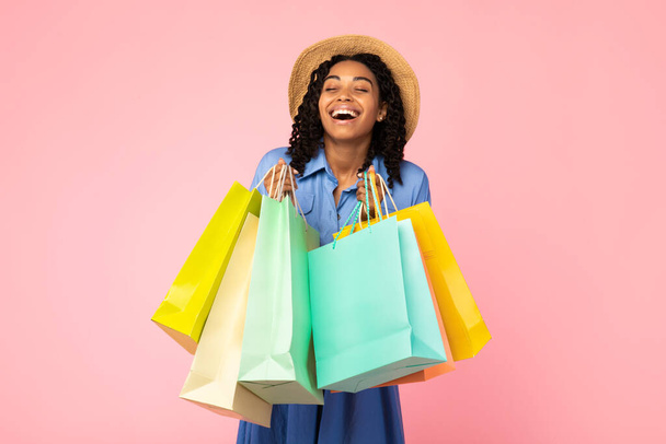 Afrykańska kobieta śmiejąc się gospodarstwa torby Shopper na różowym tle Studio - Zdjęcie, obraz