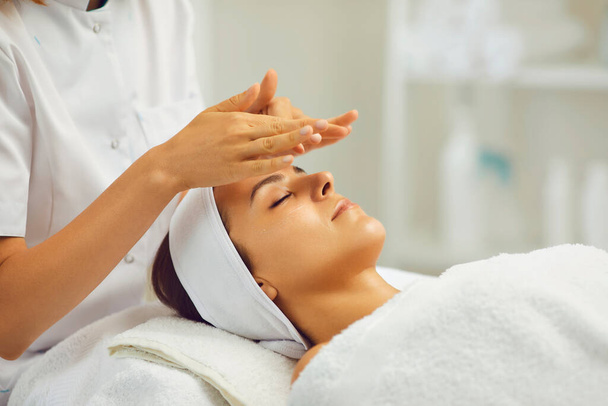 Facial massage.Beautician makes anti-age massage to a woman in a beauty salon - Фото, изображение