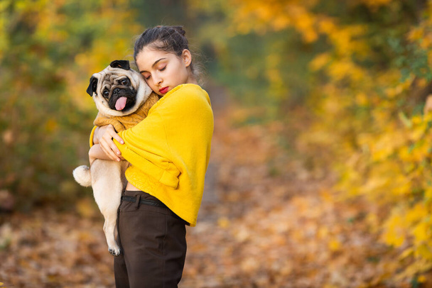 Teen girl with her dog pug in the autumn in the park. - Foto, Imagem