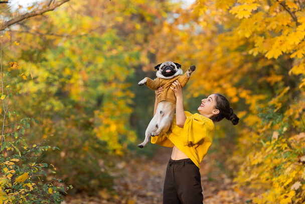Genç kız, sonbaharda parkta köpeğini kusar.. - Fotoğraf, Görsel