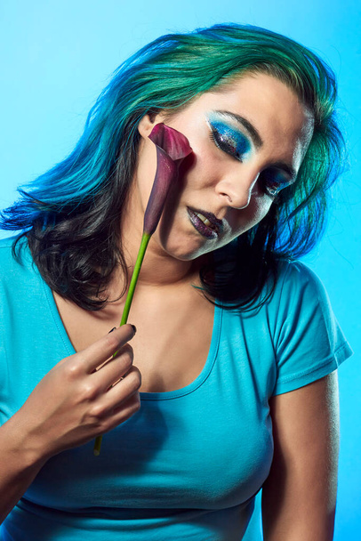 Közelkép egy fiatal nőről egy kék hátterű virággal. Szépség és divat koncepció - Fotó, kép