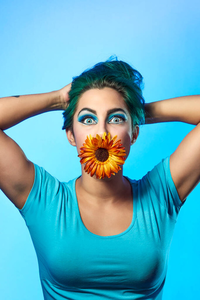 Close-up of a young woman with a flower on a blue background. Beauty and fashion concept - Photo, Image