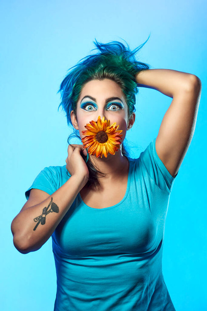 Крупный план молодой женщины с цветком на синем фоне. Концепция красоты и моды - Фото, изображение