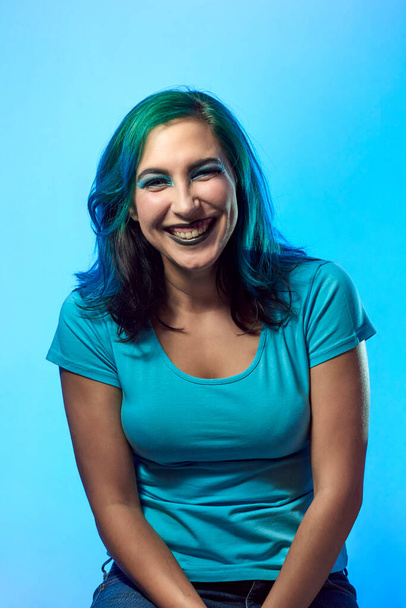 a young girl with blue hair smiling on a blue background. Beauty and fashion concept - Foto, afbeelding