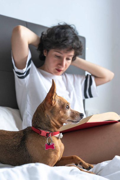 Woman reading and drinking coffee with her dog - Zdjęcie, obraz