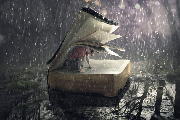 Un hombre encuentra seguridad bajo las páginas durante una tormenta de lluvia. - Foto, imagen
