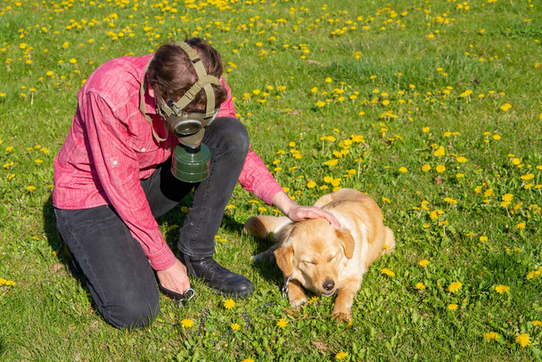 αγόρι φοράει παλιά μάσκα του ιού με το σκυλί του να παίζει στον κήπο - Φωτογραφία, εικόνα