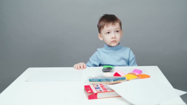 Vierjähriger Junge modelliert in Knetmasse auf grauem Hintergrund - Filmmaterial, Video