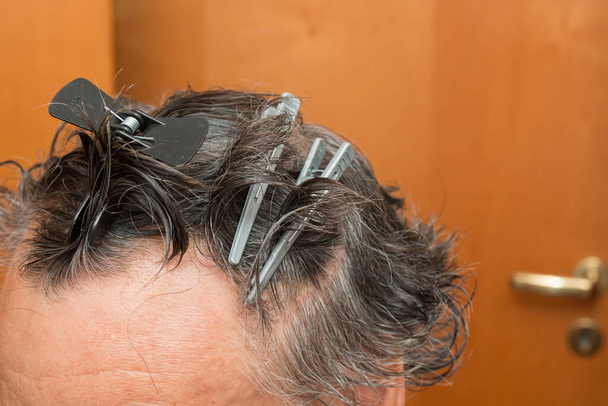 Homme âgé avec des pinces à cheveux dans ses cheveux obtenir une coupe de cheveux à la maison - Photo, image