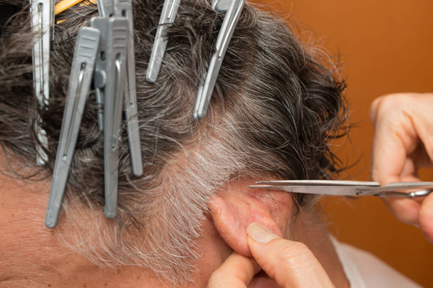 Hombre mayor con pinzas en el pelo cortándose el pelo en casa - Foto, Imagen