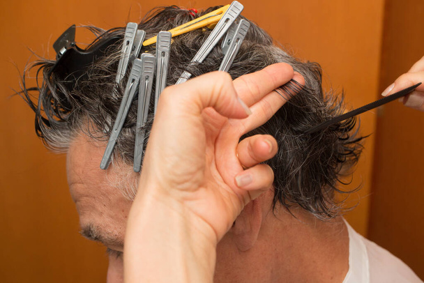 Älterer Mann mit Haarspangen im Haar bekommt zu Hause einen Haarschnitt - Foto, Bild