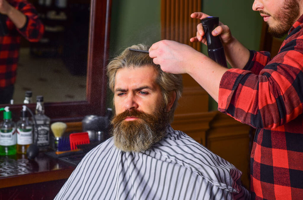 Do not cut your own hair. Hipster client getting haircut. Barber with scissors and client. Barber works on hairstyle for bearded man barbershop background. Guy with long dyed blond hair close up - Foto, Imagen