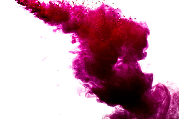 A cloud of red paint is released into the clear water. Isolate on a white background. - Фото, зображення