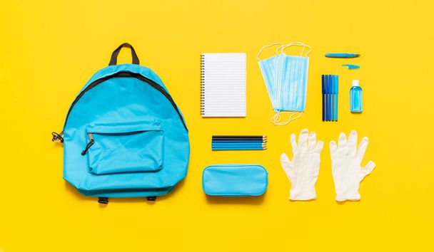 Back to school in pandemic concept. School supplies, an empty school bag and protective equipment, masks, gloves and sanitizer. New normal in school. - Photo, Image