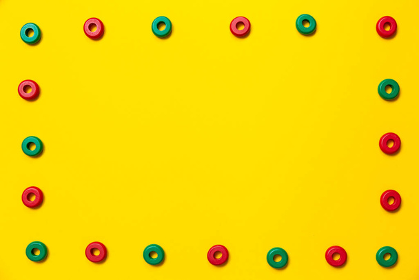 Sur un fond jaune, il y a des anneaux de couleurs vertes et rouges de la même taille, qui forment un cadre sur l'éducation et le développement des enfants. Contexte pour placer du texte et d'autres informations. - Photo, image