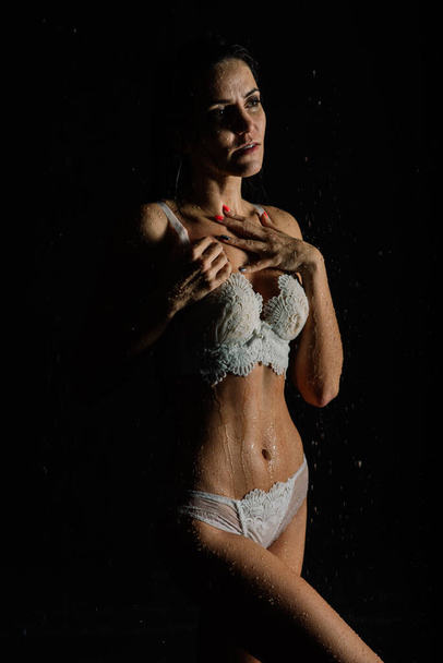 Νεαρή γυναίκα με όμορφο σπορ σώμα σε τέλειο σχήμα με σταγόνες νερού σε λευκά εσώρουχα στο aquastudio - Φωτογραφία, εικόνα