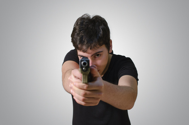 νέος που στοχεύοντας σε σας με ένα πυροβόλο όπλο - Φωτογραφία, εικόνα
