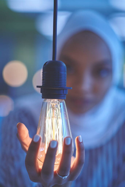 internet of things concept woman holding hands around bulb smart saving energy wearing hijab as traditional muslim - Fotoğraf, Görsel