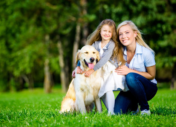 Mother and daughter with labrador are on the green grass - Valokuva, kuva