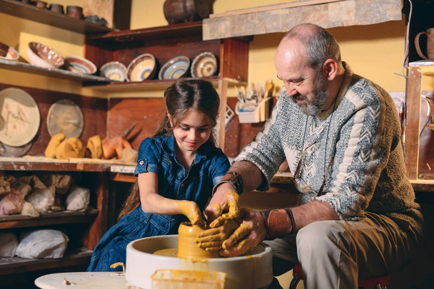 Pottery workshop. Grandpa teaches granddaughter pottery. Clay modeling - Фото, зображення