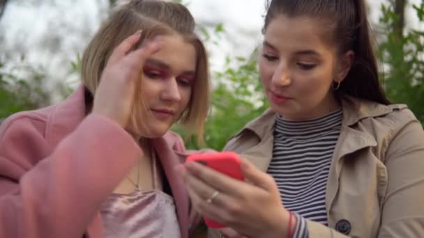 Mujeres amigas mirando la pantalla del teléfono, caminando por el parque, concepto de amistad - Imágenes, Vídeo
