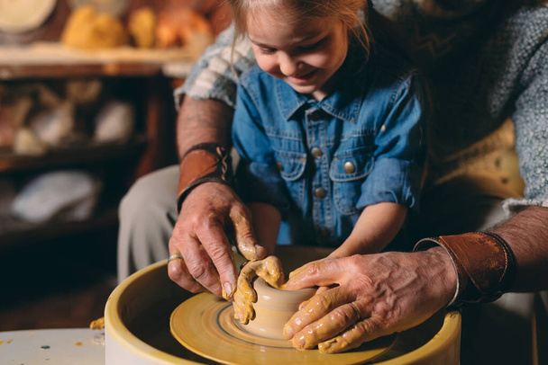 Pottery workshop. Grandpa teaches granddaughter pottery. Clay modeling - Фото, зображення