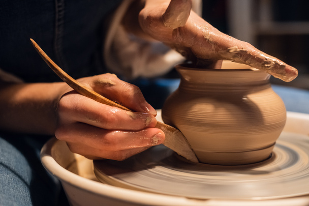 мастер в мастерской керамики показывает технику моделирования горшка на гончарном круге. - Фото, изображение