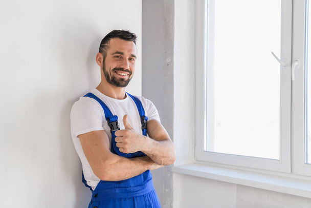 Foreman in overalls showing thumb and smiling - Foto, imagen
