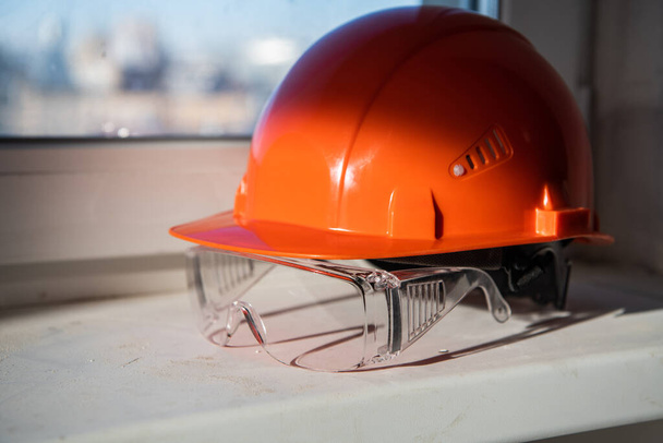 Окуляри безпеки та будівельний шолом лежать на підвіконні
 - Фото, зображення
