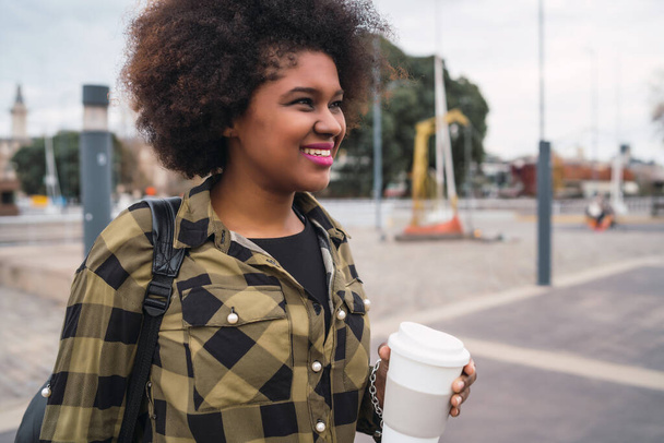 Portrait of beautiful afro american latin woman holding a cup of coffee outdoors in the street. Urban concept. - Photo, image